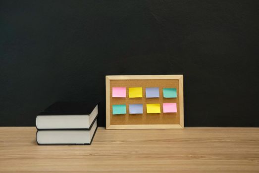 sticky notes paper reminder on cork board & book at workplace. education workspace concept