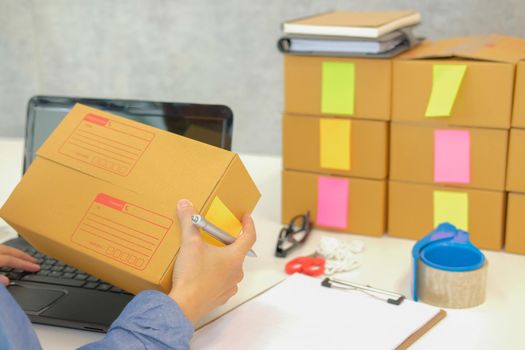 startup small business owner hold cardboard box at workplace. freelance woman entrepreneur seller prepare parcel box for delivery product to customer.  Online selling, e-commerce concept
