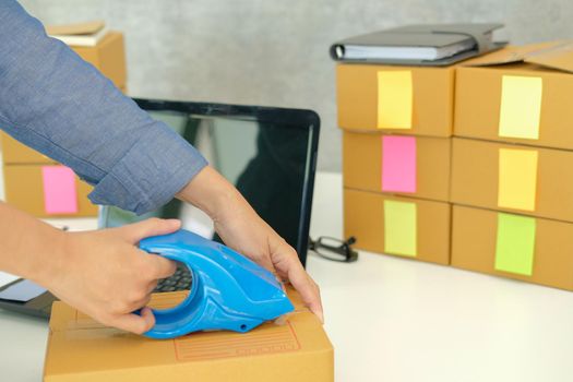 startup small business owner packing cardboard box at workplace. freelance woman entrepreneur seller prepare parcel box of product for deliver to customer.  Online selling, e-commerce concept