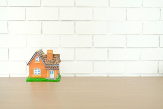 house model on wooden desk near white brick wall. realtor real estate agent workplace. buying selling & renting property
