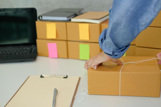 startup small business owner packing cardboard box at workplace. freelance woman entrepreneur seller prepare product parcel box for deliver to customer. Online selling, e-commerce concept