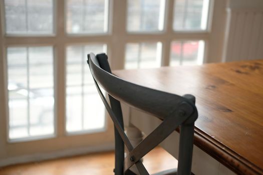 chair & wood table near white window in cozy dining room