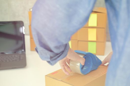 startup small business owner packing cardboard box at workplace. freelance woman entrepreneur seller prepare parcel box of product for deliver to customer.  Online selling, e-commerce concept