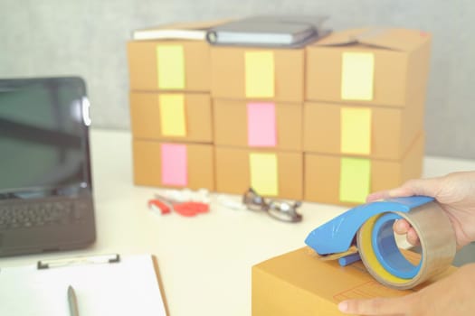 startup small business owner packing cardboard box at workplace. freelance woman entrepreneur seller prepare parcel box of product for deliver to customer.  Online selling, e-commerce concept