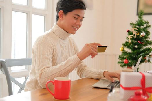 man holding credit card for online shopping. male buyer buying christmas gift on internet. new year holiday merry xmas celebration