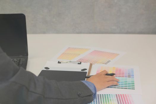 graphic interior designer choosing color from swatch sample catalogue palette guide at workplace. artist design & idea for creativity project.