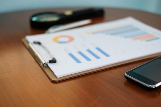 graph chart document, pen & magnifying glass on office table