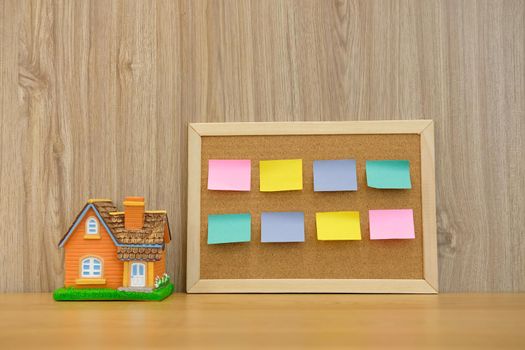 sticky notes paper reminder on cork board & house model on wooden desk. real estate investment. property buying mortgage loan