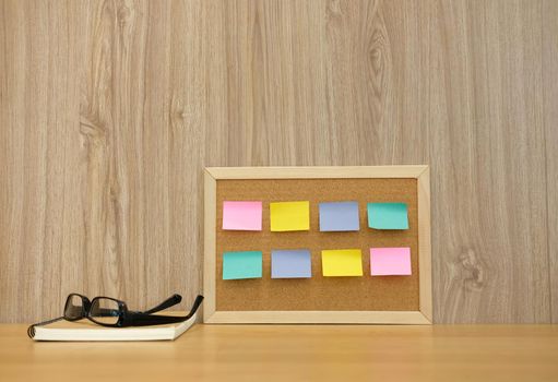 sticky notes paper reminder on cork board & notebook at workplace. education workspace concept