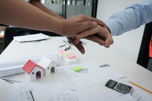 architect & customer joining hands at workplace. Engineer put hand together with partner for successful deal in building project development. business teamwork concept