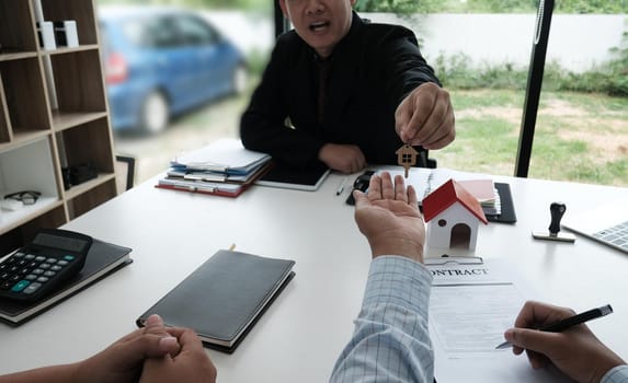 real estate agent have a meeting with customer. sale & purchase property with house model, key and signing contract document. realtor talk with client.