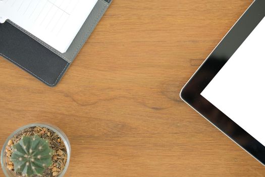 tablet notebook on wooden desk table. office workplace workspace top view. succulent cactus plant in pot. education concept