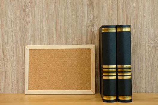 blank cork board & book on wooden desk at workplace. education workspace concept