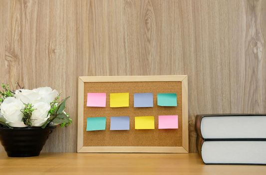 sticky notes paper reminder on cork board & book at workplace. education workspace concept