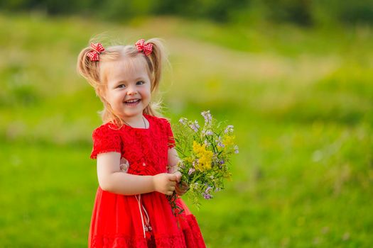 girl in a red dress and with a bouquet of wild flowers on the lawn