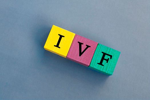 IVF acronym on colorful wooden cubes against blue background. In Vitro Fertilization. Flat lay. Copy Space. Directly above.