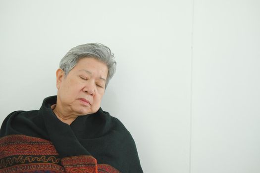 elder woman taking a nap. asian elderly female senior napping sleeping near white wall