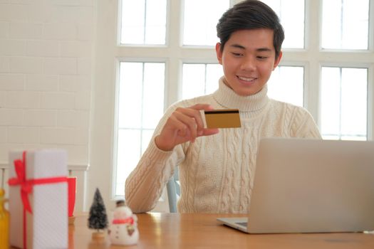 man holding credit card for online shopping. male buyer buying christmas gift on internet. new year holiday merry xmas celebration