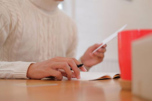 man wearing cream sweater writing christmas letter greeting card holiday wishes. xmas celebration.