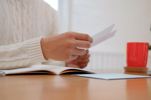 man wearing cream sweater opening sending christmas letter greeting card holiday wishes. xmas celebration