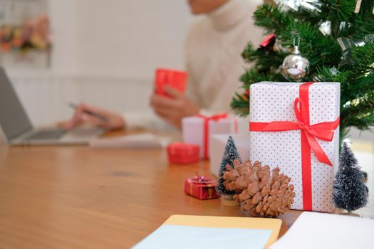 man wearing cream sweater holding coffee cup & using computer at home during christmas. xmas new year celebration