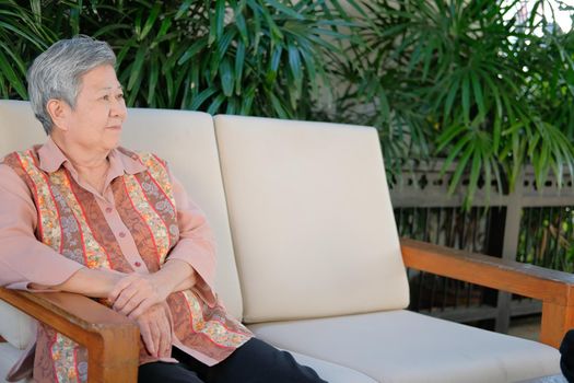 old cheerful elderly woman smiling relaxing at home. happy elder senior sit on sofa in garden