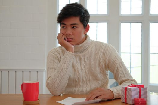 man wearing cream sweater thinking what to write on christmas letter greeting card holiday wishes. xmas celebration