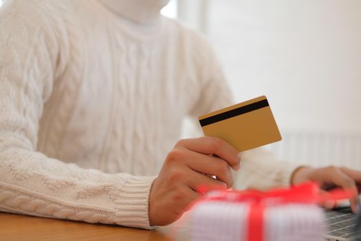 man holding credit card for online shopping. male buyer buying christmas gift on internet. new year holiday merry xmas celebration