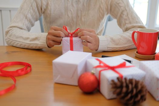 man wearing cream sweater wrapping christmas gift present box. xmas new year holiday celebration.