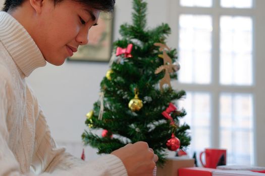 man wearing cream sweater wrapping christmas gift present box. xmas new year holiday celebration.