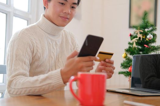 man holding credit card & smart phone for online shopping.  male buyer buying christmas gift on internet. merry xmas new year holiday celebration