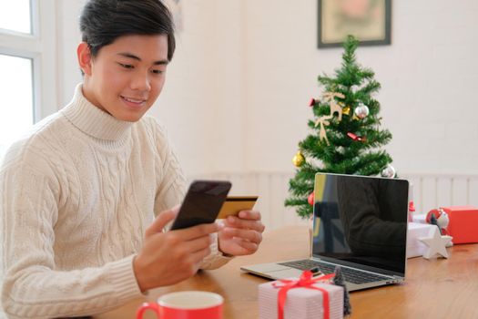 man holding credit card & smart phone for online shopping.  male buyer buying christmas gift on internet. merry xmas new year holiday celebration