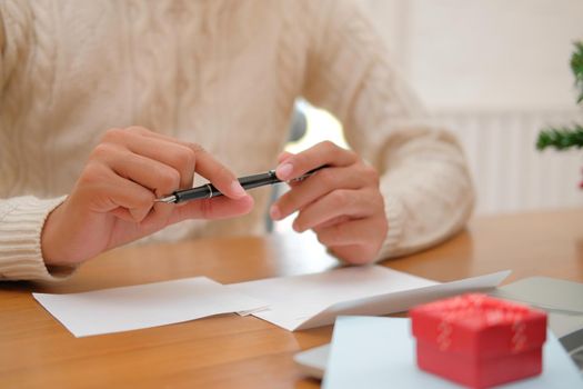 man wearing cream sweater thinking writing christmas letter greeting card holiday wishes with xmas decoration.