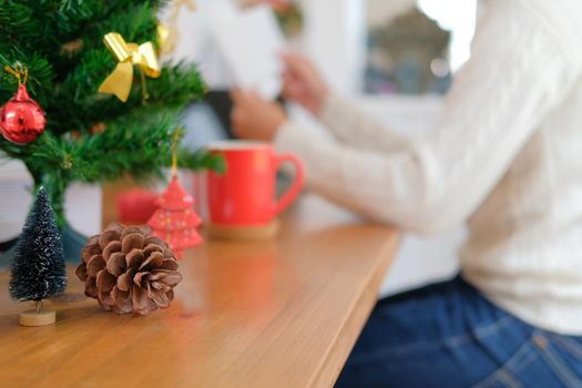 man wearing cream sweater opening sending christmas letter greeting card holiday wishes with xmas decoration