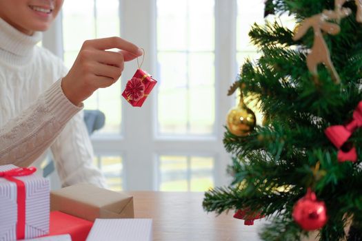 man wearing cream sweater decorating christmas tree. xmas new year holiday celebration.