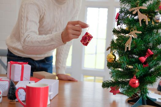 man wearing cream sweater decorating christmas tree. xmas new year holiday celebration.