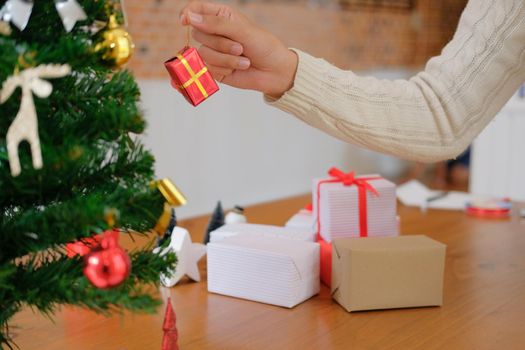 man wearing cream sweater decorating christmas tree. xmas new year holiday celebration.