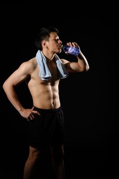 portrait of athletic muscular bodybuilder man with naked torso six pack abs drinking water. fitness workout concept