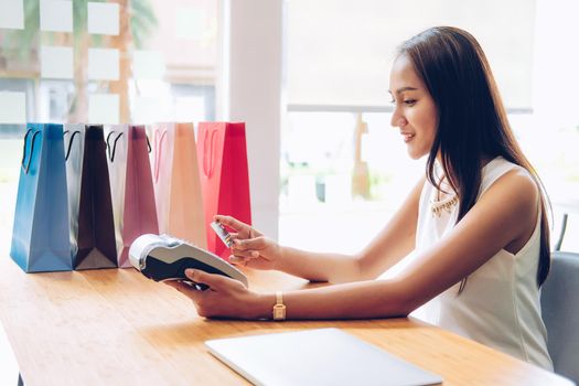 woman using credit card swiping machine with shopping bags on table. cashless payment with nfc technology