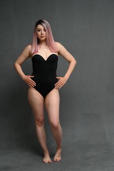 Full length Photo large size woman in a swimsuit on a gray background. Front view