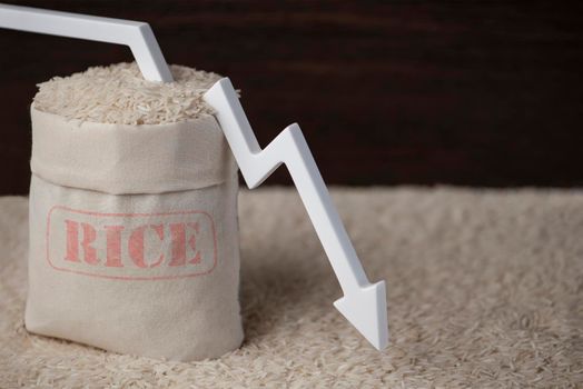 Rice harvest. Poor agricultural crops, food shortages, world hunger. A bag of rice on a brown background with a white arrow pointing down