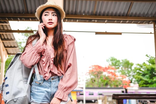 woman traveler with backpack talking on mobile smart phone at train station. trip journey travel concept