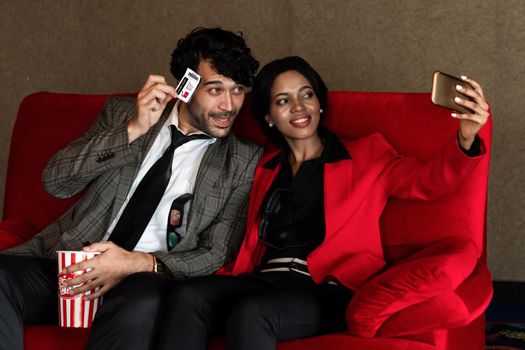 A couple man and woman take a photo with a ticket while sitting and waiting In front of the cinema