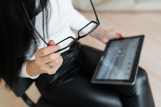 A young business girl solves problems online on a tablet. Young woman chatting on a virtual online conference. The concept of communication is not in the office, online work