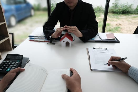 hand protecting house model. client signing home insurance contract. property safety and security concept