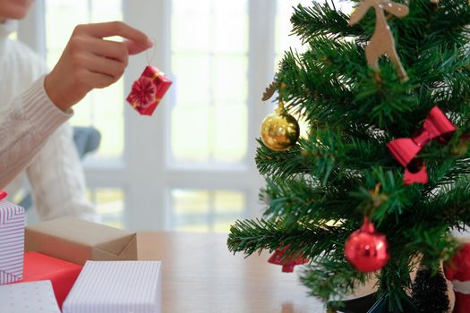 man wearing cream sweater decorating christmas tree. xmas new year holiday celebration.