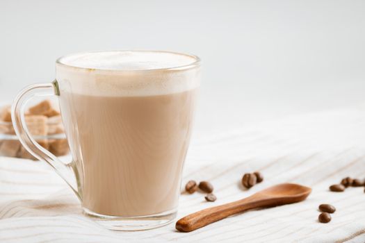 Latte coffee with foam on a light kitchen table, copy space.