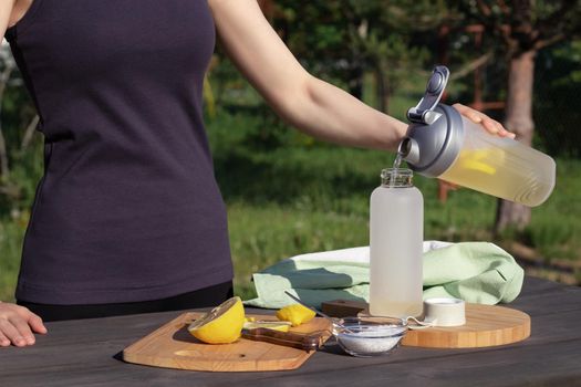 Girl makes a fresh homemade isotonic drink from natural ingredients - salt, lemon and mineral water.