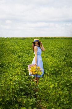 beautiful girl in a hat and blue board is standing on a green field.