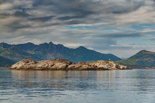 Norwegian seascape, rocky coast with dramatic skies, the sun breaks through the clouds, sheer cliffs, small islands illuminated by the sun. High quality photo